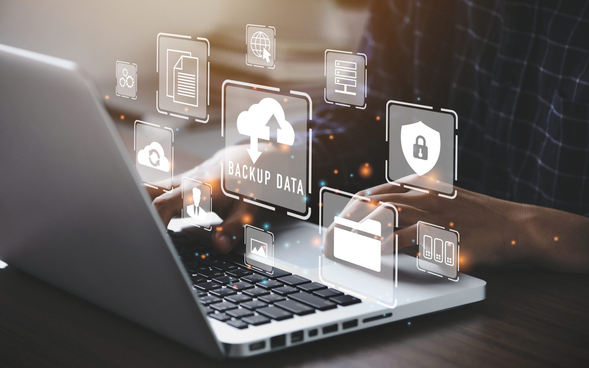 Hands typing with data backup icons overlay